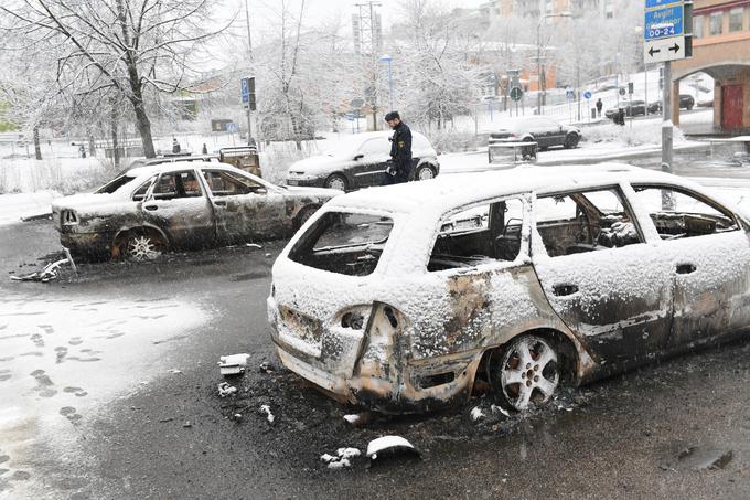 Švedski policist med avtomobili, ki so jih v soseski Rinkeby pred dnevi zažgali izgredniki. | Foto: Reuters