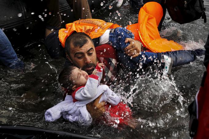 Sirski begunec drži svoja otroka, medtem ko želi po preplutju dela Egejskega morja priti s čolna na grški otok Lezbos, 24. september 2015. | Foto: Reuters