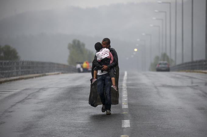 Sirski begunec poljublja svojo hčer, medtem ko ob nevihti hodi proti grški meji z Makedonijo v bližini kraja Idomeni, 10. september 2015. | Foto: Reuters