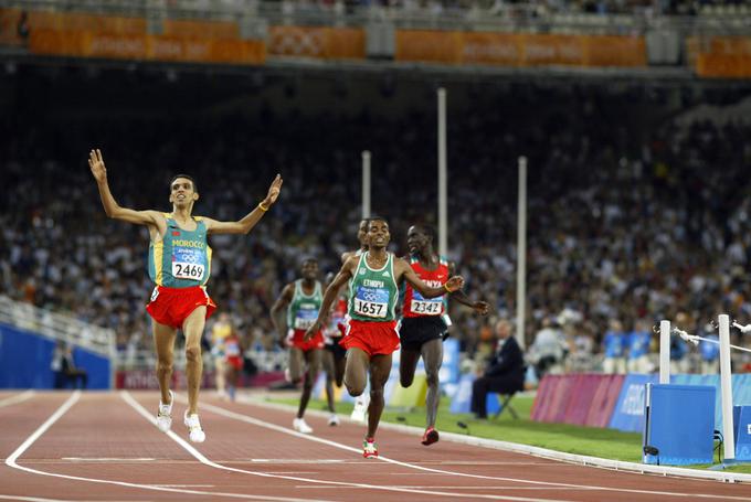 Že na olimpijskih igrah leta 2004 v Atenah smo videli nov obračun treh tekaških velikanov v teku na 5000 metrov. Takrat je zlato medaljo osvojil El Guerrouj, sicer svetovni rekorder v teku na 1500 metrov, pred Bekelejem in Kipchogejem. | Foto: Reuters