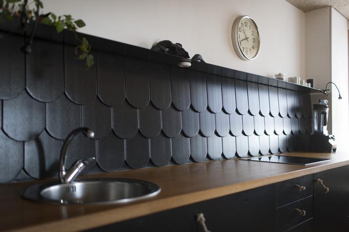 Na steni nad kuhinjskim pultom in štedilnikom ni klasičnih ploščic, temveč črn bobrovec. V kuhinji, kot pravi arhitekt Goran Rupnik, so si privoščili nekaj humorja. | Foto: 