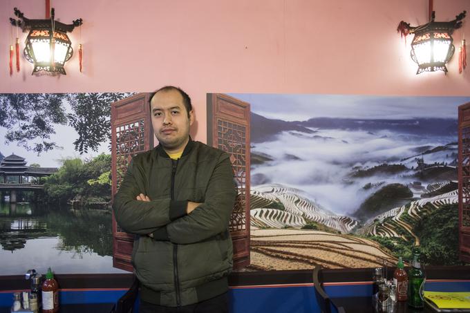 Huang pred fotografijo kitajskega mesta Fang Cheng Gang, od koder prihaja njegova družina. Tako kot v Ljubljani v mestu živi okrog 250 tisoč prebivalcev.  | Foto: Matej Leskovšek