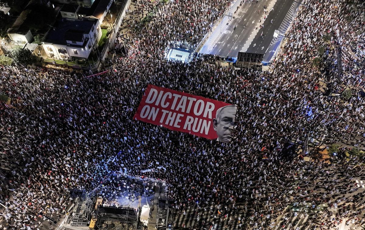 Protesti v Izraelu | Na velikem transparentu z rdečim ozadjem, ki so ga nosili demonstranti v Tel Avivu, je ob sliki predsednika vlade Benjamina Netanjahuja pisalo: "Diktator na begu." | Foto Reuters