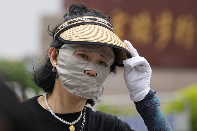 Ženska se je v Šanghaju pred vročino in soncem zakrila s posebno obrazno masko in pokrivalom. | Foto: Reuters