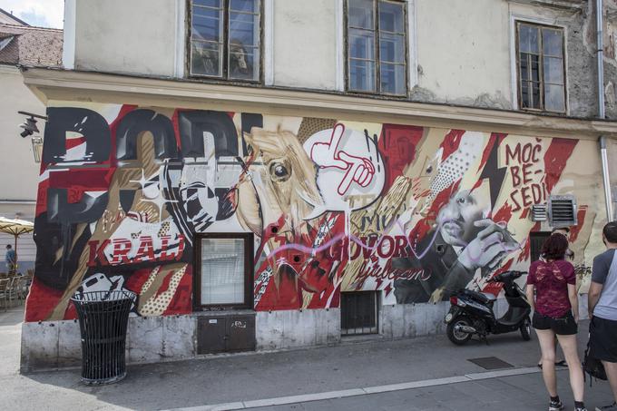 Naročen, legalen in komercialen grafit pri Zlati ladjici: nastal je kot del kampanje Mobitela oz. Telekoma Slovenije z naslovom Moči besed. To je bila pobuda, ki je opozarjala na nevarnosti sovražnega govora na spletu med mladim. V okviru te so nastali grafiti v Ljubljani, Mariboru in Kopru. Avtor pričujočega je ulični umetnik Teoson. V grafitarski skupnosti prav naročeni in komercialni grafiti, ki so v svobodi izražanja omejeni, odpirajo številna vprašanja. Kot kritiko, provokacijo in znak tega je mogoče prebirati tudi roza črto, ki se je pred kratkim pojavila čez poslikavo.   | Foto: Matej Leskovšek