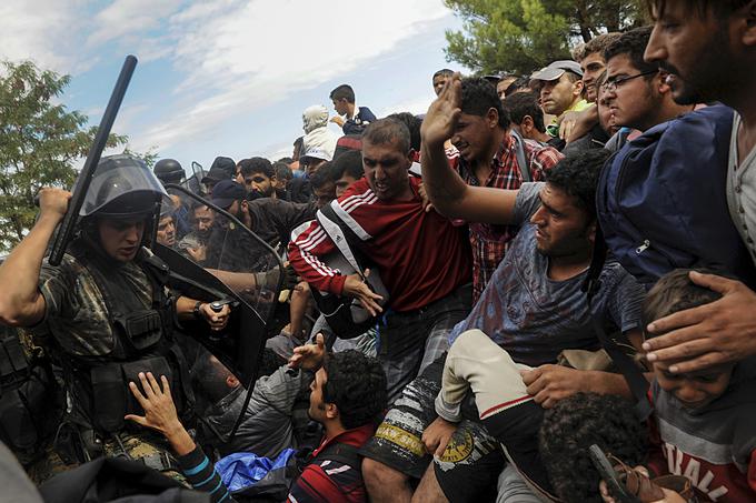 Makedonski policist se je na grški meji blizu kraja Idomeni s palico spravil na migrante, da bi jim preprečil vstop v Makedonijo, 22. avgust 2015. | Foto: Reuters