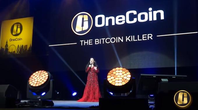 Ruja Ignatova pred leti na dogodku za promocijo kriptovalute onecoin. Osrednji slogan, zaradi katerega so ljudje množično kupovali izobraževalne pakete, s katerimi so dobili žetone, ki so jih nato porabili za rudarjenje onecoinov, je bil, da je "Onecoin ubijalec bitcoina". Onecoin so na promocijskih dogodkih namreč najraje primerjali z najbolj prepoznavno kriptovaluto in izpostavljali njene slabosti, ki naj bi jih onecoin domnevno odpravil. | Foto: YouTube