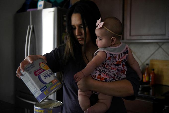 Kim Anatra s svojo petmesečno hčerko Sienno, ko v posodo pretresa še zadnjo zalogo mlečne formule, medtem ko se družina med nenehnim pomanjkanjem v državi trudi najti hrano za dojenčka. | Foto: Reuters