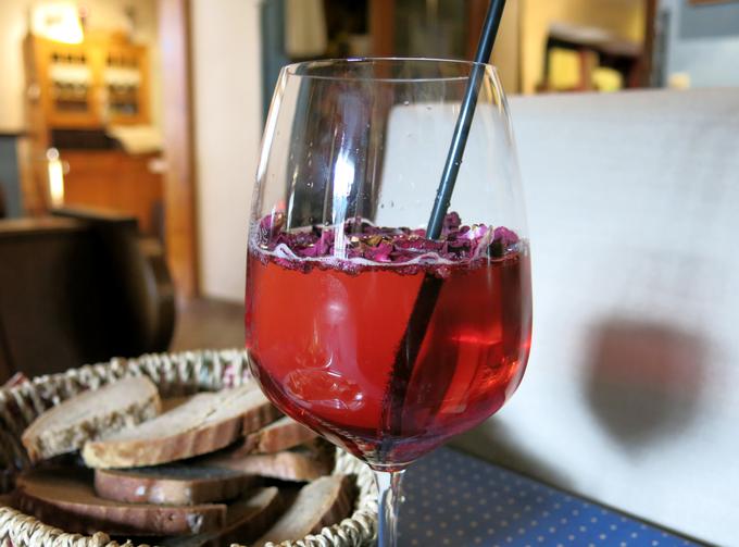Hišnemu koktajlu z rožnatim vinom in vrtničnim likerjem dodajo posušene cvetne liste vrtnice. | Foto: Miha First