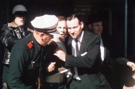 Lee Harvey Oswald po aretaciji (v sredini, med obema policistoma). | Foto: commons.wikimedia.org
