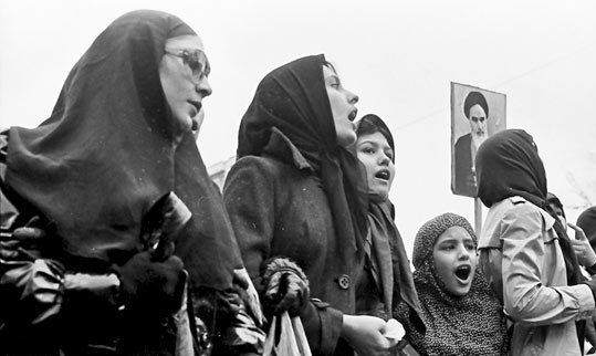 Leta 1936 je šah Reza Pahlavi, ki je želel posodobiti iransko družbo po zahodnem zgledu, prepovedal nošenje hidžaba in čadorja. Te prepovedi v versko konservativni družbi šah ni mogel popolnoma uveljaviti, še zlasti ne na podeželju. V 70. letih preteklega stoletja je hidžab postal simbol upora proti šahu Mohamedu Rezi Pahlaviju, sinu Reze Pahlavija. To naglavno pokrivalo so v znak protesta začele nositi tudi mestne ženske iz srednjega sloja. Na fotografiji iz obdobja islamske revolucije vidimo skupino žensk s hidžabi in fotografijo ajatole Homeinija. | Foto: Thomas Hilmes/Wikimedia Commons