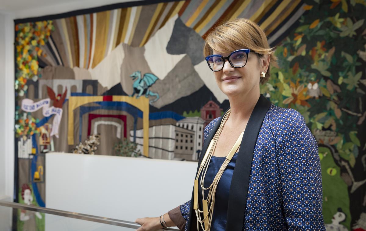 Center Rog. Renata Zamida | Center Rog je dostopen vsakomur. Tu se lahko obiskovalci učijo, ustvarjajo, izdelujejo, klepetajo, družijo. "Hiša je vsak dan polna in to nas najbolj veseli," je za Siol povedala direktorica centra Renata Zamida. V ozadju je ogromna skupnostna tapiserija Vse, kar delamo, je naše. Ideja je nastala oktobra 2023 ob vselitvi v prenovljeno stavbo. Motive je izrisala prva udeleženka rezidenčnega programa Centra Rog Lea Kirstein iz Nemčije. | Foto Bojan Puhek