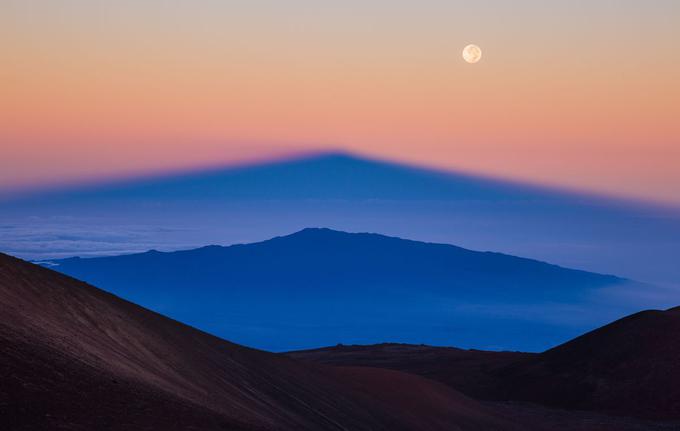 Senca havajskega ognjenika Mauna Kea, ki jo vzhajajoče sonce meče na vulkan Hualalai. Od dneva se zgoraj poslavlja polna luna. Foto: Sean Goebel. | Foto: 