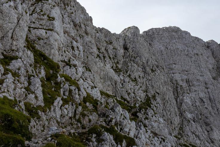 Na začetku zahtevnega dela je ozka steza z jeklenicami, nato pa se je treba povzpeti po steni navzgor, a je ta lepo varovana. Vrh je na fotografiji viden desno zgoraj. | Foto: Matej Podgoršek