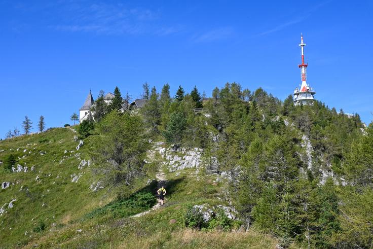 Ko pridemo iz strnjenega gozda, se nam odpre pogled proti vrhu s cerkvijo in oddajnikom. | Foto: Matej Podgoršek