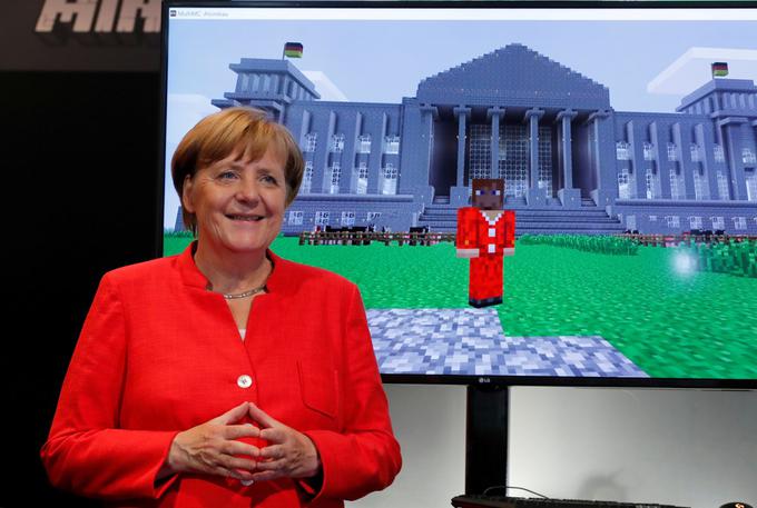 Nemška kanclerka Angela Merkel pozira ob svojem liku, ki stoji pred virtualno repliko v Minecraftu zgrajene stavbe nemškega parlamenta oziroma Reichstaga.  | Foto: Reuters