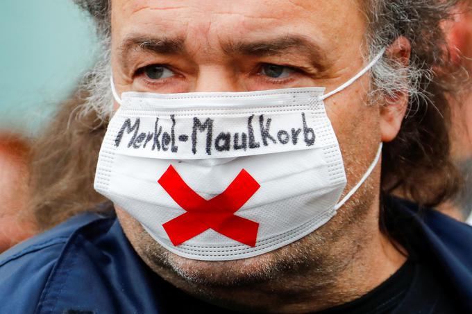 V Nemčiji se zadnje čase krepijo nasprotniki strogih zajezitvenih ukrepov. Na fotografiji vidimo nasprotnika ukrepov, ki ima na zaščitni maski napis Merkel-Maulkorb (sl. Merklov nagobčnik). | Foto: Reuters