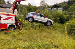 Avto zapeljal čez strmo brežino in obstal na betonskem podpornem zidu