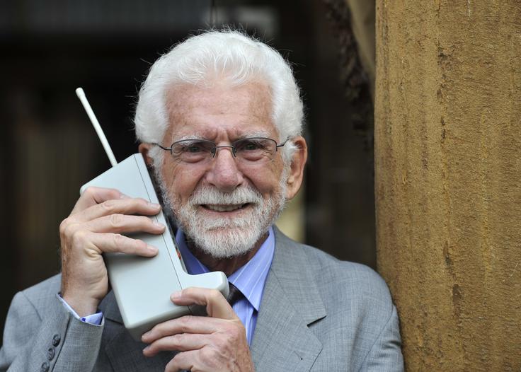Martin Cooper ali Marty Cooper je izumil prvi pravi mobilni telefon. Na fotografiji ga drži v roki. Naprava, ki tehta okrog enega kilograma, je Motorola DynaTAC. Prvi prototip je Cooper naredil že leta 1973, mobilnik pa je Motorola v več različicah nato prodajala od leta 1984 do 1994. Ko se je prvi DynaTAC pojavil na prodajnih policah v ZDA, je bilo zanj treba odšteti okrog štiri tisoč dolarjev, upoštevajoč inflacijo bi zanj danes morali plačati kar 8.500 evrov. | Foto: Reuters