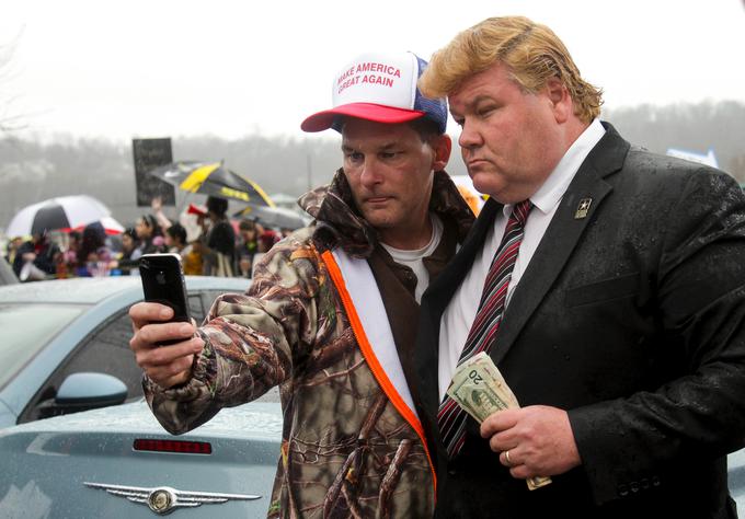 Oboževalec se fotografira z oponašalcem Donalda Trumpa, ki v roki drži dolarske bankovce. (Trump se rad pohvali s svojim večmilijardnim premoženjem.) | Foto: Reuters