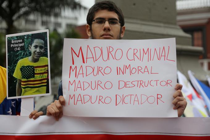 "Maduro - kriminalec, Maduro - nemoralnež, Maduro - uničevalec, Maduro - diktator," piše na protestnikovem transparentu. | Foto: Reuters