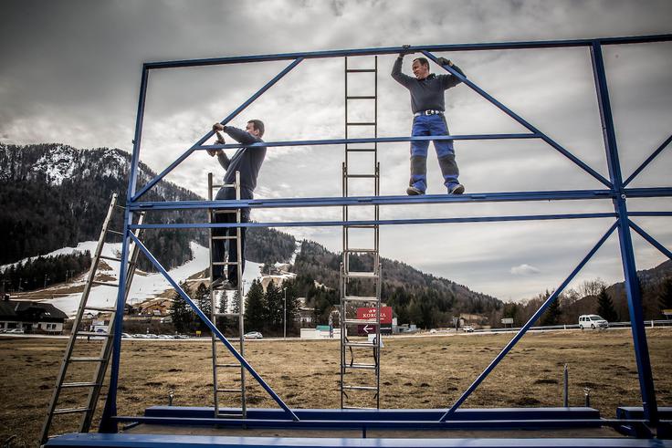 Prvi znaki, ki kažejo na priprave na planiški skakalni praznik, so vidni že v Kranjski Gori. Delavci so pripravljali ogrodje za postavitev plakatov, ki bodo vabili v zibelko slovenskih smučarskih skokov. | Foto: Vid Ponikvar
