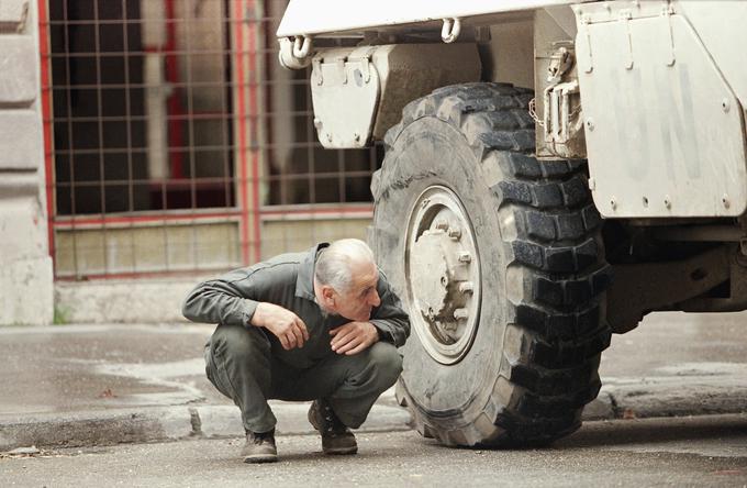 Neznani moški se pred ostrostrelci skriva za vojaškim vozilom. Fotografija je bila posneta 7. junija 1995. | Foto: Guliverimage/Vladimir Fedorenko