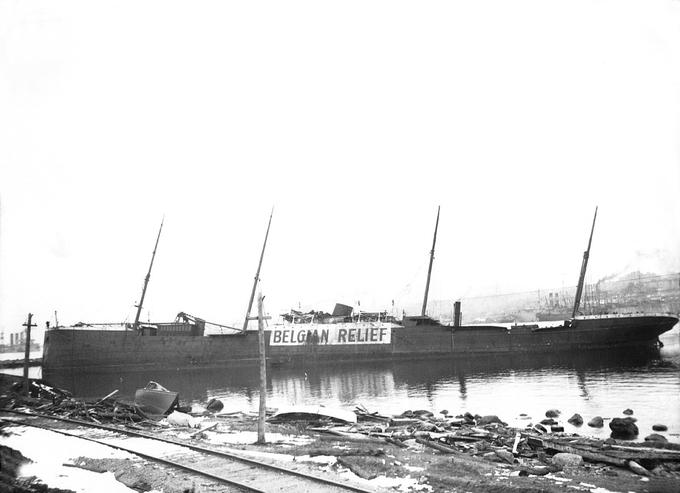 Ladja SS Imo po eksploziji v Halifaxu. Na boku je imela napis Belgian Relief, s čimer je morebitnim agresorjem - nenazadnje je plula v času prve svetovne vojne - sporočala, da gre za humanitarno plovilo.  | Foto: Thomas Hilmes/Wikimedia Commons