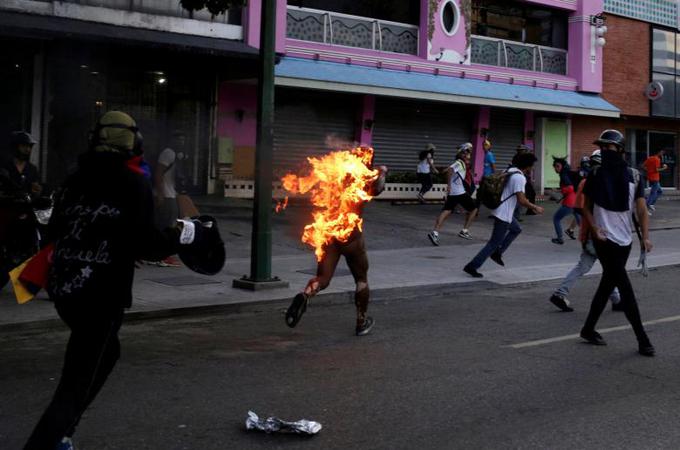 Goreči moški, obtožen kraje, sredi opozicijskih navijačev v Caracasu, Venezuela. Vir: Reuters | Foto: 