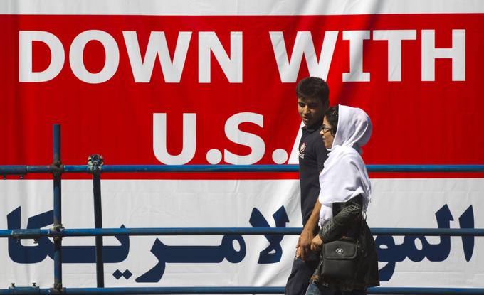 Iran je država, ki je že od leta 1979 sovražnica ZDA. Na fotografiji: mlad par v Teheranu gre mimo zidu, na katerem je napis Dol z ZDA (Down with U.S.A.). | Foto: Reuters