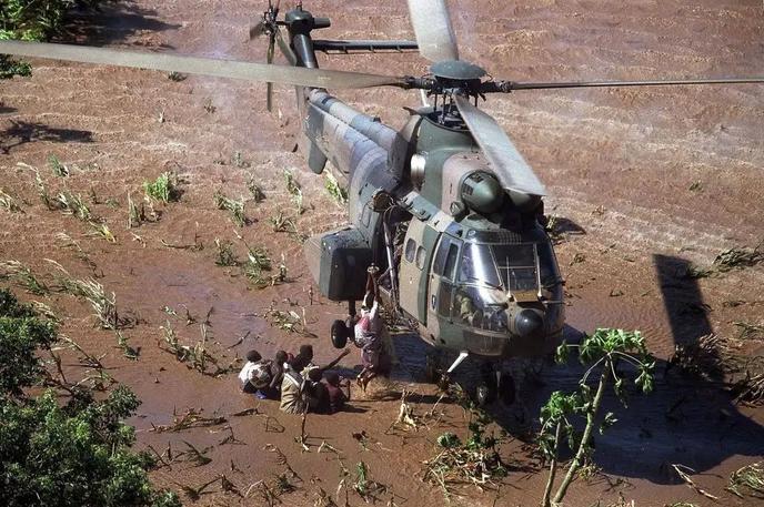 Deklica | Pogled na novorojenčka in mater, ki ju je helikopter prepeljal na varno sredi poplavljene pokrajine, je postal prepoznavna podoba mozambiških poplav leta 2000 – najhujših v Mozambiku doslej. | Foto FB/Gabinete de informação, imagem e comunicação da cidade de Chibuto