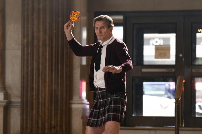 Gola pištola, Naked Gun | Liam Neeson kot Frank Drebin v zdaj že memeficirani prvi sceni, ko se razkrije preoblečen v šolarko s (smrtonosno) lizalko. | Foto Karantanija Cinemas