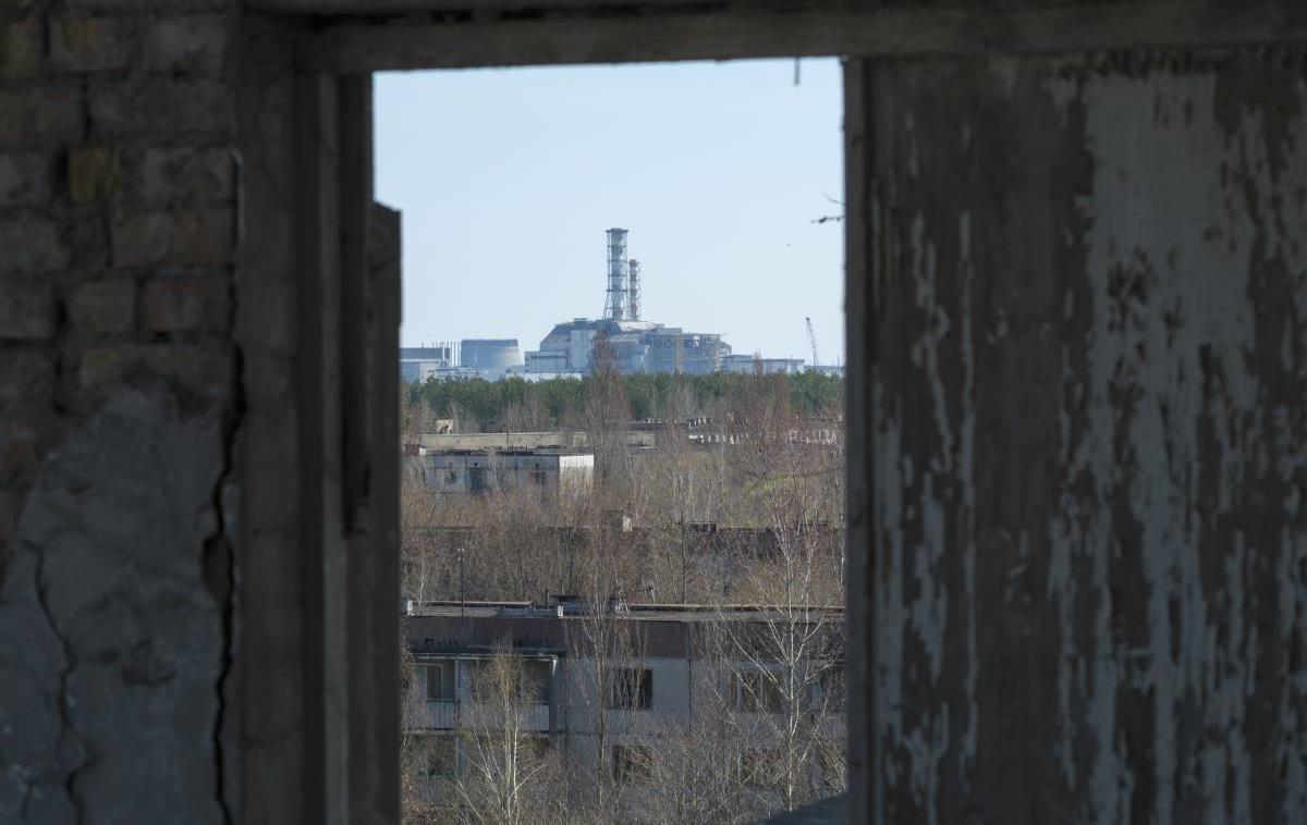Černobil, Pripjat | Černobilska jedrska elektrarna skozi okno enega od blokov v zapuščenem mestu Pripjat. Fotografija je bila posneta še pred začetkom gradnje nove zaščitne kupole, s katero so leta 2017 prekrili še vedno sevajoči del elektrarne. | Foto Reuters