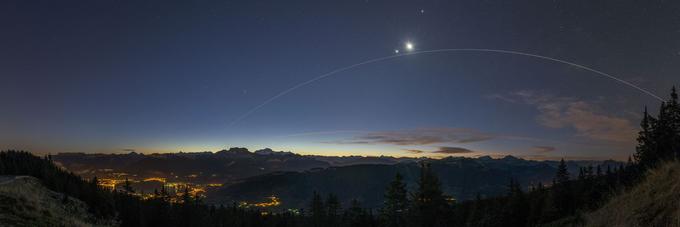 Lok svetlobe, ki ga je med potjo okrog Zemlje nad francoskim mestom Annecy za sabo pustila Mednarodna vesoljska postaja (ISS). Visoko na nebu tesno skupaj sijeta Luna in planet Venera. Foto: Scott Carnie Bronca. | Foto: 