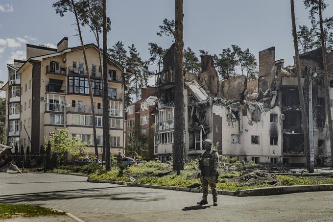 Vojak stoji pred uničenimi stavbami v ukrajinskem kraju Irpin. | Foto: Guliverimage/Vladimir Fedorenko
