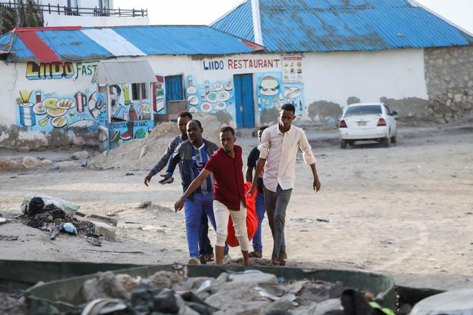 napad v Mogadišu | Moški nesejo truplo ženske, ubite v napadu skrajne islamistične skupine Al Šabab, na plažo Lido v Mogadišu.  | Foto Reuters