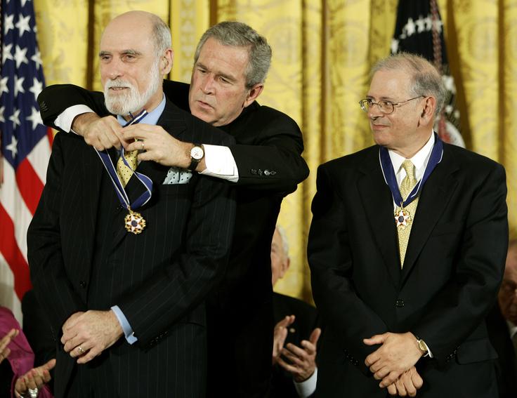 Ameriška računalniška inženirja Robert Kahn in Vinton Cerf sta leta 1974 svetu predstavila pomembna izuma: protokol za prenos podatkov (Transmission Control Protocol) in internetni protokol (Internet Protocol). Oba bolj poznamo po njunih kraticah oziroma združeni kratici TCP/IP. Gre za temeljna komunikacijska protokola, na katerih je zasnovan internet. Kahn in Cerf zaradi tega veljata tudi za očeta interneta. Na fotografiji Robert Kahn (desno) in Vinton Cerf (levo) prejemata nacionalno odlikovanje ZDA za dosežke na področju znanosti in tehnologije. Cerfu odlikovanje okrog vratu pripenja nekdanji predsednik ZDA George Bush mlajši.  | Foto: Reuters