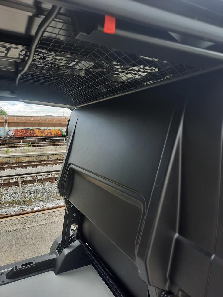 Sedala in naslonjala klopi v navpičnem položaju tvorijo zaščitno steno med kabino in prtljažnikom, mreža pa se umakne pod strop. Klop se vrne v izhodiščni položaj s potegom rdečega trakca, ki je (samo) na desni strani.

 | Foto: Aleš Črnivec