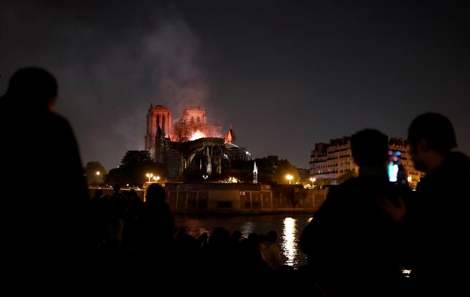 Na ulicah, trgih in mostovih v bližini katedrale se je zbralo na stotine ljudi, ki v tišini in žalosti opazujejo plamene. | Foto: Reuters