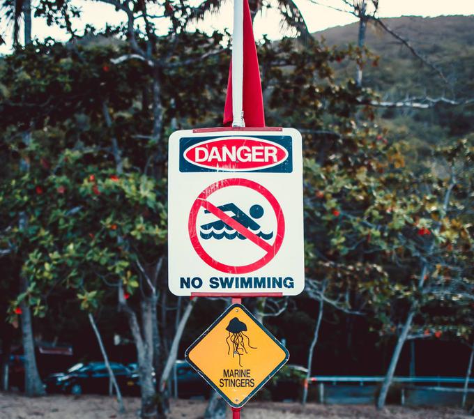 "Plavanje prepovedano zaradi morskih ožigalkarjev." Takšnih znakov, ki jih spremlja rdeča zastava, je na plažah severovzhodne Avstralije kar nekaj. Kubomeduze, med katerimi so tudi meduze irukandji, ob plavalcih sicer najpogosteje ogrožajo tudi potapljače, ki raziskujejo Veliki koralni greben. Avstralski biologi sicer opozarjajo, da so srečanja z meduzami irukandji in drugimi kubomeduzami glede na število plavalcev in potapljačev redka, a v regijah, kjer živijo te meduze, kljub temu svetujejo plavanje in potapljanje v oblekah iz neoprena.  | Foto: Thinkstock