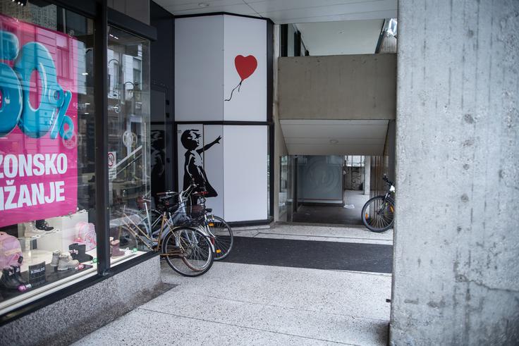 Slovita Banksyjeva Deklica z balonom ob vhodu v razstavni prostor na Čopovi | Foto: Gaja Hanuna