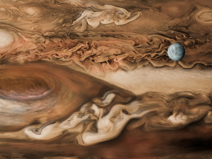 V ozadju Jupiter, v ospredju njegova luna Evropa. Gre za barvno predelavo legendarne sestavljene fotografije, ki jo je leta 1979 posnelo vesoljsko plovilo Voyager 1. Klikni na sliko za izvirnik. | Foto: NASA