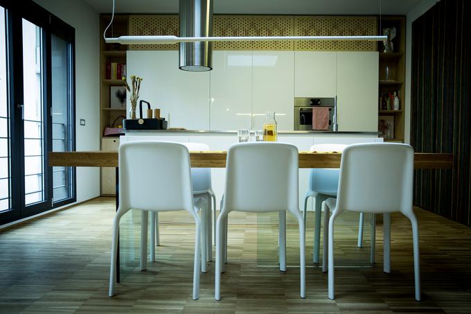 Osrednji prostor, namenjen druženju, v stanovanju predstavlja dnevna soba s kuhinjo in jedilno mizo, ki se navzven odpira z okni do tal. | Foto: Ana Kovač