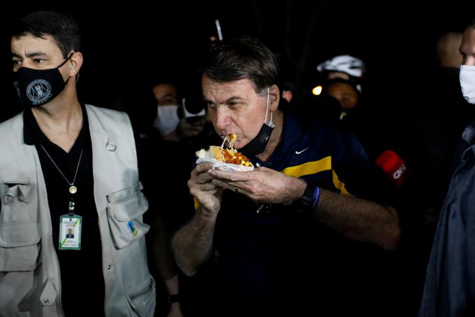 Brazilski predsednik Jair Bolsonaro med epidemijo novega koronavirusa uživa v hot dogu na ulici. | Foto: Reuters