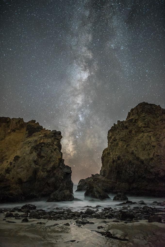 Naša galaksija Rimska cesta med dvema velikima skalama na eni od plaž v Kaliforniji. Disk galaksije je viden povsod, kjer je svetlobna onesnaženost minimalna. Če jo želite videti, se ponoči podajte iz mesta na podeželje ali v hribe. Foto: Rick Whitacre. | Foto: 