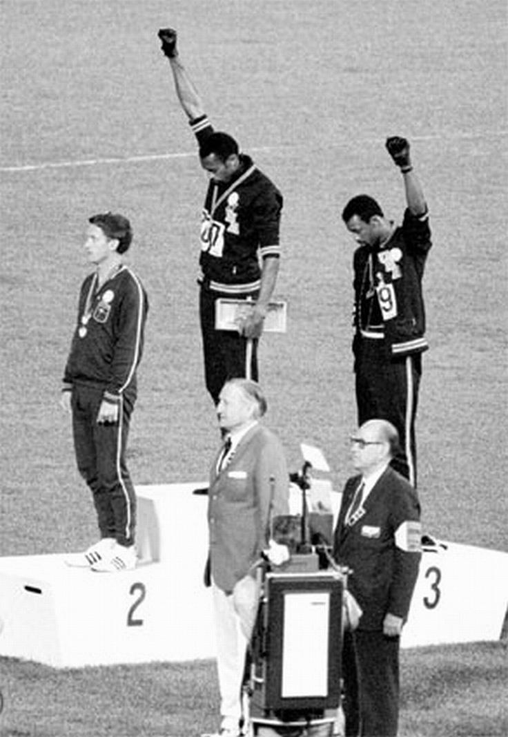 Američana Tommie Smith in John Carlos sta na zmagovalni oder v teku na 200 metrov prikorakala brez čevljev, obuta le v črne nogavice, ki so predstavljale revščino temnopoltih ljudi. Smith je imel okoli vratu ovit črn šal, ki je predstavljal črnski ponos, Carlos pa je imel odpet zgornji del trenirke v znak solidarnosti z delavskim razredom v ZDA in ogrlico okoli vratu, ki je po njegovih besedah simbolizirala vse, ki so bili linčani, ubiti, obešeni in vrženi v morje med prevozom iz Afrike v ZDA v času trgovanja s sužnji, ne da bi kdo za njih molil. | Foto: Guliverimage/Vladimir Fedorenko