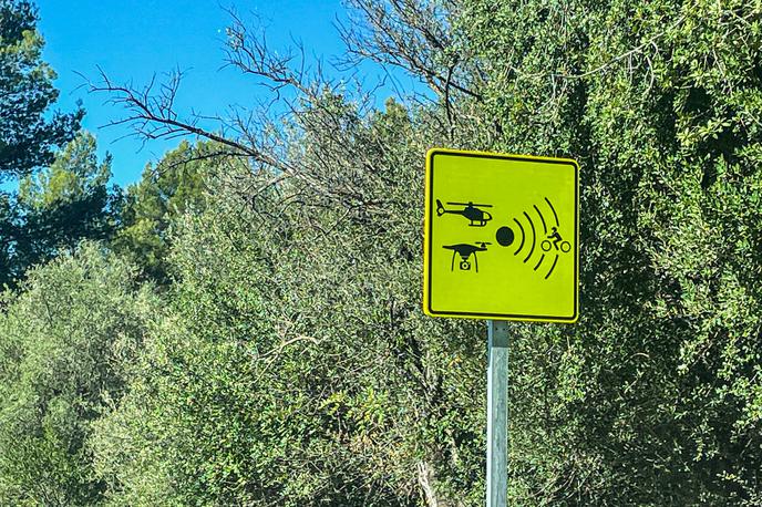 Dron nadzor policija Španija | Tabla, ki opozarja voznike motociklov, da jih lahko pri vožnji nadzoruje tudi brezpilotnik oziroma dron. | Foto Gašper Pirman