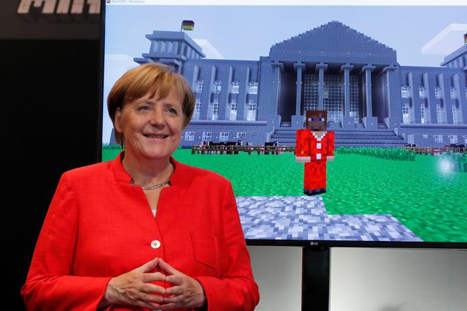 Angela Merkel med govorom na sejmu gamescom pozira pred televizijskim zaslonom, na katerem je kanclerka upodobljena v znani računalniški igri Minecraft, za njo pa stoji prav tako v Minecraftu narejeni nemški Reichstag.  | Foto: Reuters