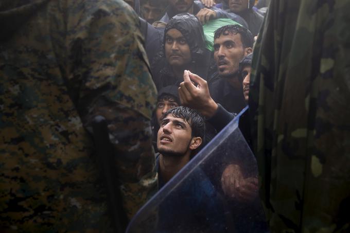  Begunci in migranti prosijo makedonskega policista, naj jim dovoli prečkati mejo iz Grčije v Makedonijo med nevihto blizu vasi Idomeni, 10. septembra 2015. | Foto: Reuters