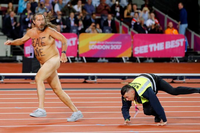 Varnostnik neuspešno lovi moškega aktivista, ki je nag pritekel na prizorišče svetovnega prvenstva v atletiki v Londonu, avgust 2017. | Foto: Reuters